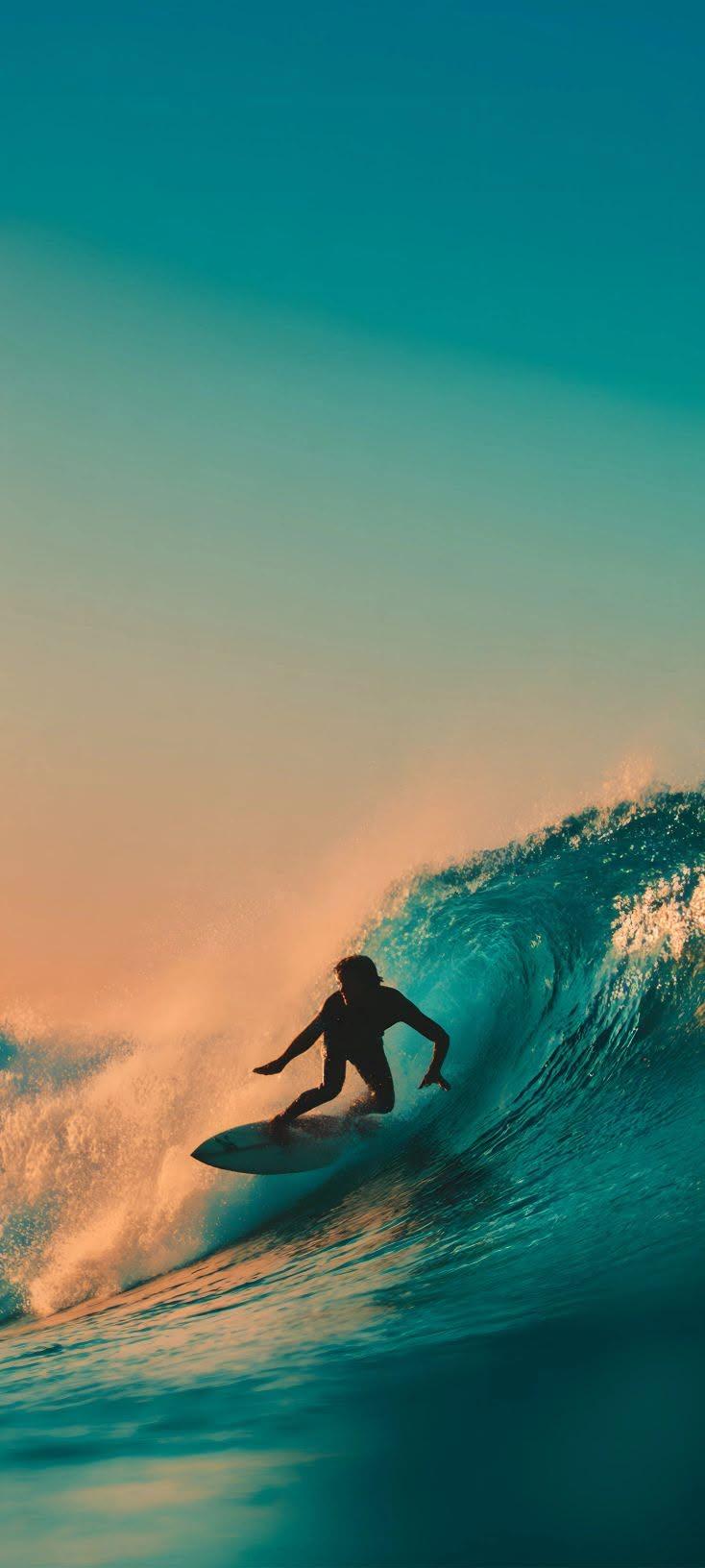 Sunset Surfer Riding Turquoise Ocean Wave Wallpaper